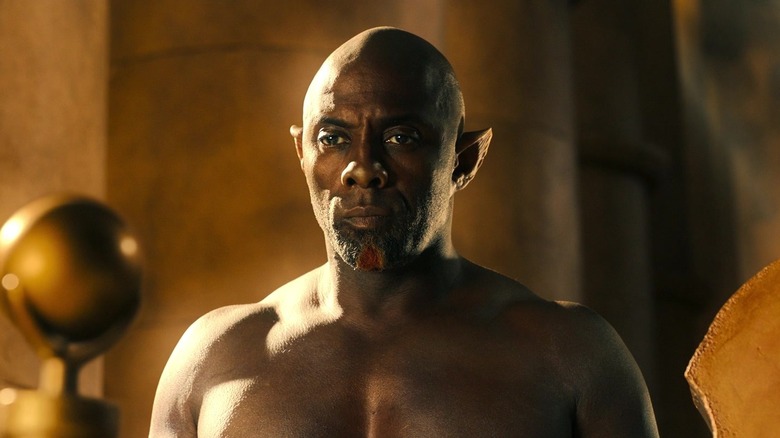 Idris Elba as Djinn standing shirtless in a palace with a scowl in Three Thousand Years of Longing