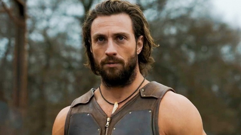 Aaron Taylor-Johnson as Kraven standing in front of the woods in Kraven the Hunter