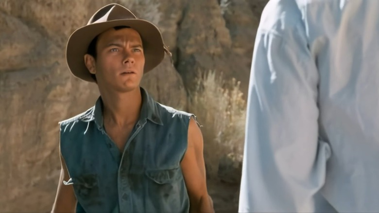 Boy looks concerned in a denim vest and brown hat in Dark Blood