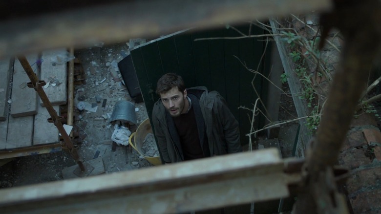 Jamie Dornan as Paul Spector in The Fall watches a woman below her apartment