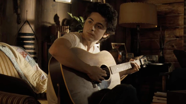 Timothee Chalamet as Bob Dylan playing guitar in A Complete Unknown