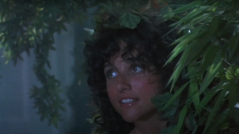 Young Julia-Louis Dreyfus standing in room surrounded by plants