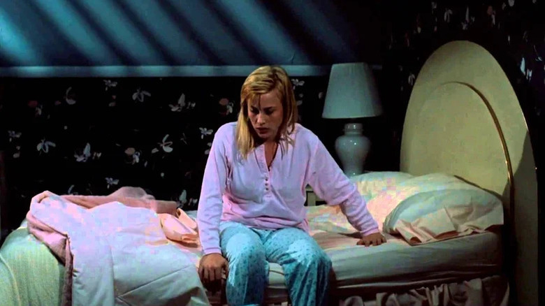 Young Patricia Arquette sitting on bed in pajamas