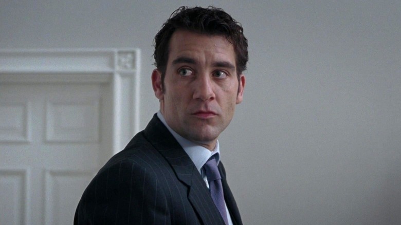 Clive Owen as Larry Gray wearing a suit and tie and looking over his shoulder in Closer