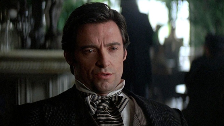 Hugh Jackman as Robert Angier sitting down and speaking in The Prestige