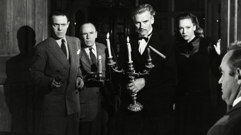 Dr. Edward G. Armstrong (Walter Huston) holding a candle among other guests in 1945's And Then There Were None