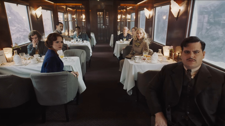 Hector (Josh Gad), Mary (Daisy Ridley), Linda (Michelle Pfeiffer), and other sitting in dining cart in 2017's Murder on the Orient Express