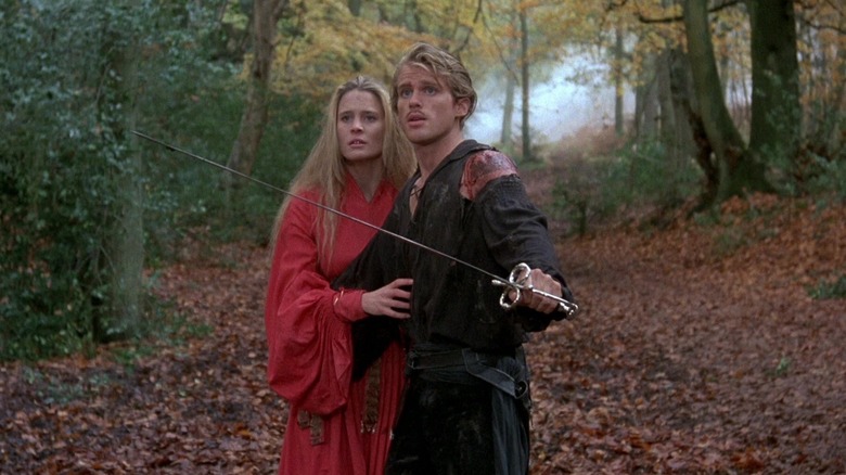 Cary Elwes as Westley holding a sword as he protects Robin Wright's Buttercup in The Princess Bride