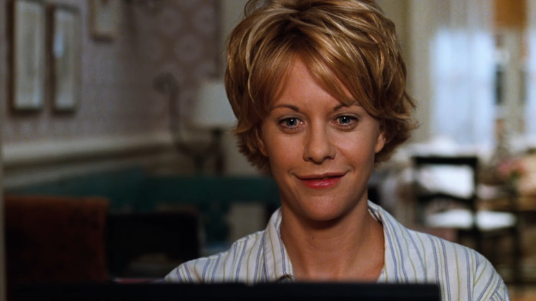 Meg Ryan as Kathleen Kelly smiling and reading the computer screen in You've Got Mail