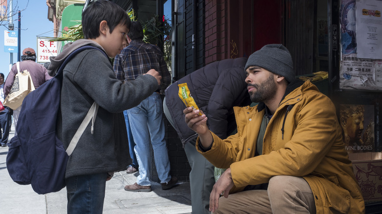 Kingsley Ben-Adir as Karim Washington holding up a bag of candy to a kid on The OA