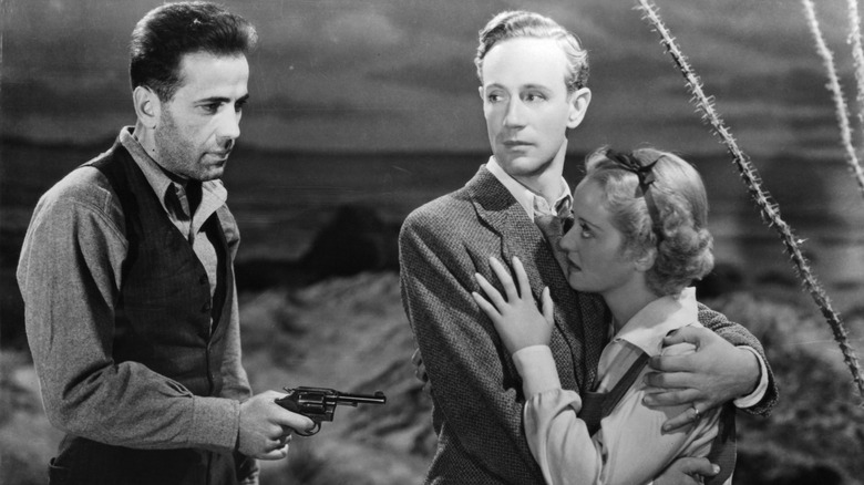 Duke Mantee (Humphrey Bogart) threatens Alan Squier (Leslie Howard) and Gabrielle Maple (Bette Davis) in The Petrified Forest