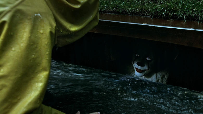 Bill Skarsgård as Pennywise speaks to a child from a sewer in It