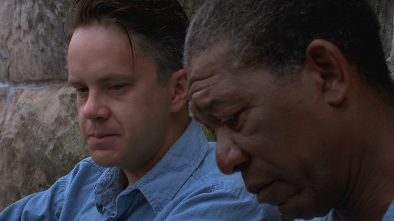 Tim Robbins as Andy Dufresne sits next to Morgan Freeman as Ellis Boyd Redding in The Shawshank Redemption