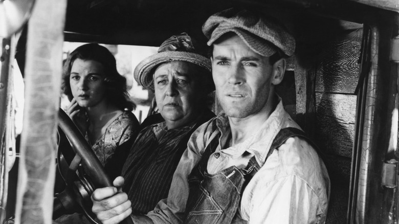 Tom Joad (Henry Fonda) sits in a 1930s car with his family in The Grapes of Wrath