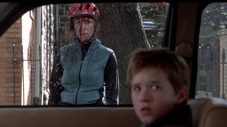 Cole looking scared with a dead bloodied biker behind him in The Sixth Sense