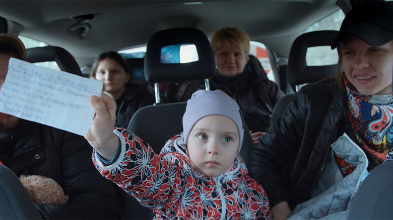 Child holding paper in backseat