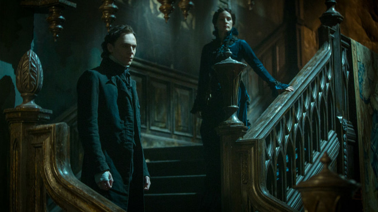 Tom Hiddleston and Jessica Chastain pose on a gothic staircase