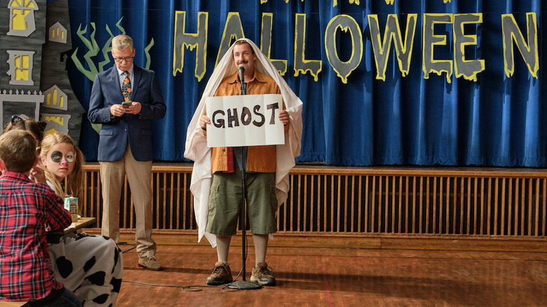 Adam Sandler holds a sign reading "Ghost"