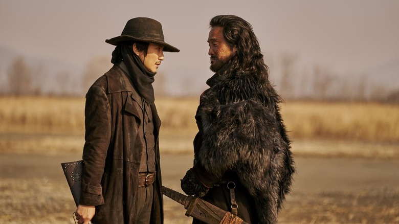 Lee Yoon (Kim Nam-gil) speaks to a bandit while holding a rifle in Song of the Bandits