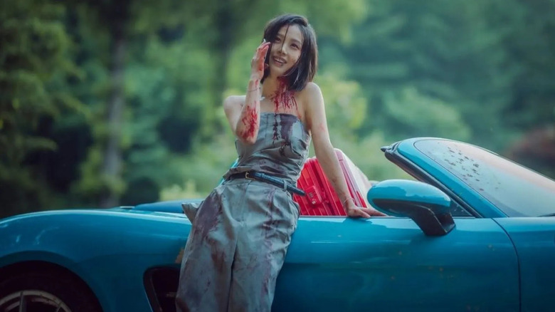 A bloody Yoo Seong-a (Go Min-si) answers her phone by her car in The Frog