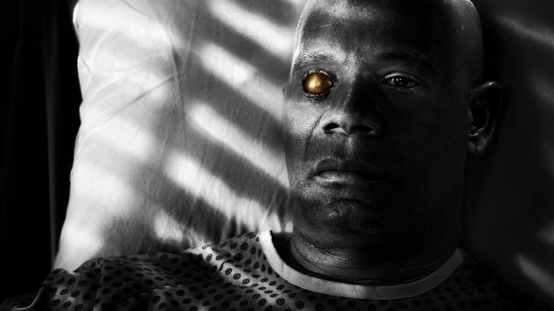 Manute (Dennis Haysbert) lies in bed, his golden eyeball the only thing colorized, in Sin City 2