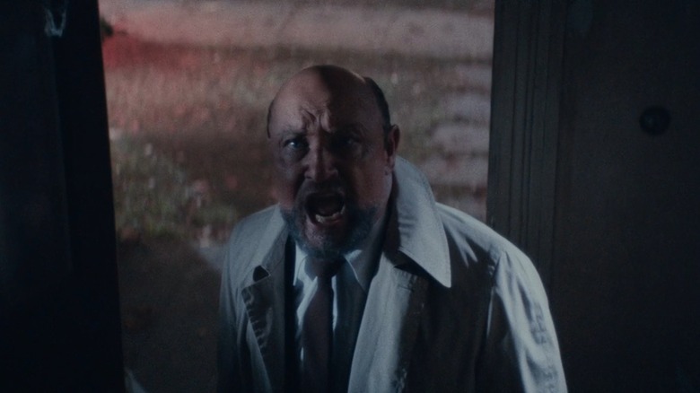 Tom Jones Jr. as Dr. Loomis yells while standing in front of an open front door, in Halloween Kills