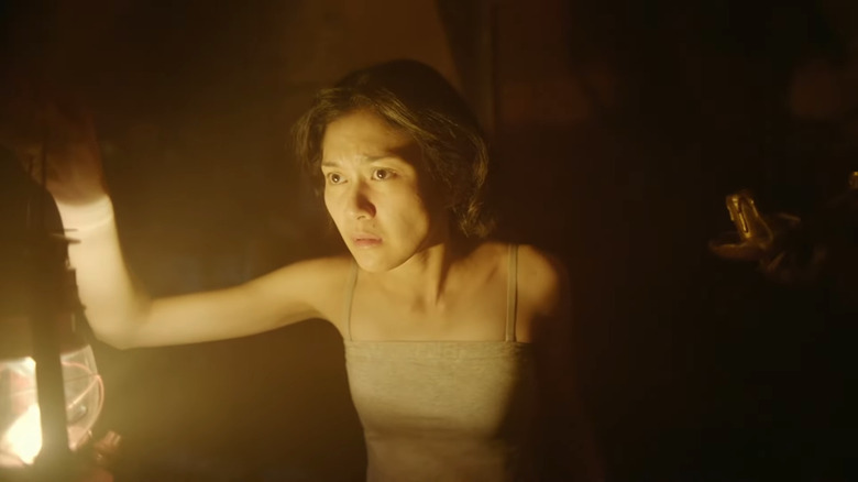 Woman holding lantern in dark room