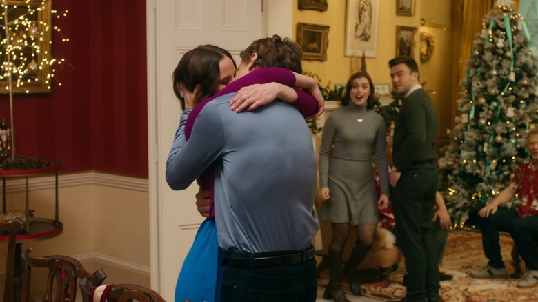 Georgia and Graham kiss in front of a Christmas tree and delighted family members in Christmas in Notting Hill