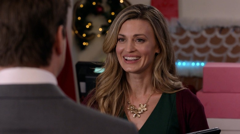 Ellie smiles at a man in a suit in her bakery in Christmas In Love