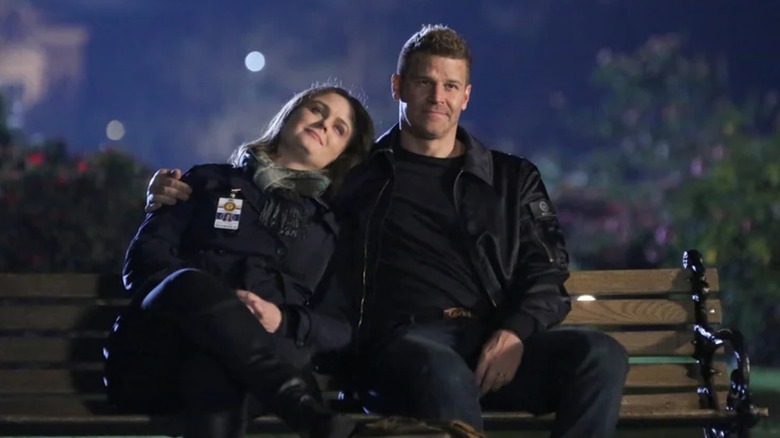 Emily Deschanel's Brennan leans on David Boreanaz's Booth's shoulder while they sit on a bench in Bones