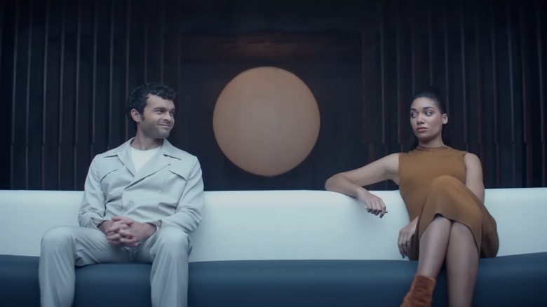 Alden Ehrenreich as John the Savage, smiling at a woman on a couch on Peacock's adaptation of Brave New World