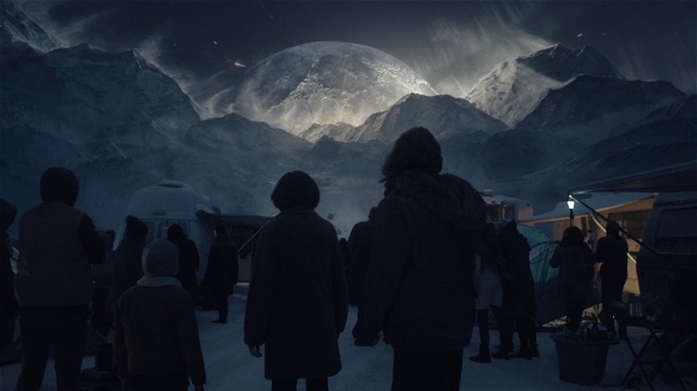 Crowd watches moon over mountains