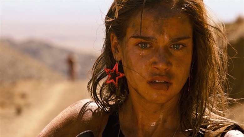 Matilda Lutz standing dirty and bloodied in desert in Revenge