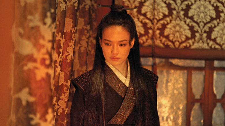 Shu Qi standing in front of red curtains in The Assassin