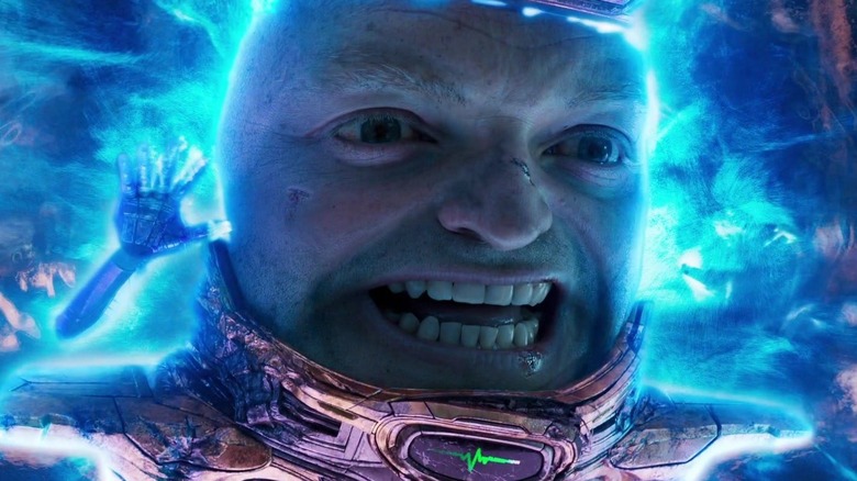 Corey Stoll as M.O.D.O.K. pulling a face and dashing in Ant-Man and the Wasp: Quantumania