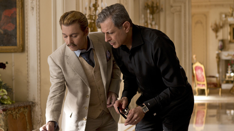 Johnny Depp's Charlie Mortdecai and Jeff Goldblum's Milton Krampf examining a piece of artwork in Mortdecai