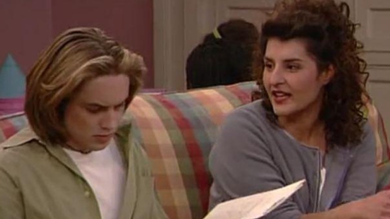 Will Friedle's Eric looks at a paper file while sitting next to Nia Vardalos' Mrs. Gallagher on a couch on Boy Meets World