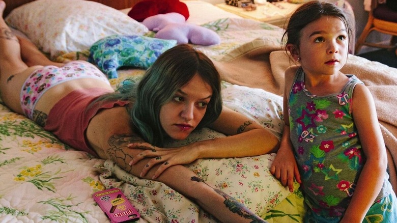 Halley (Bria Vinaite) lays on a bed next to Moonee (Brooklynn Kimberly Prince) in The Florida Project