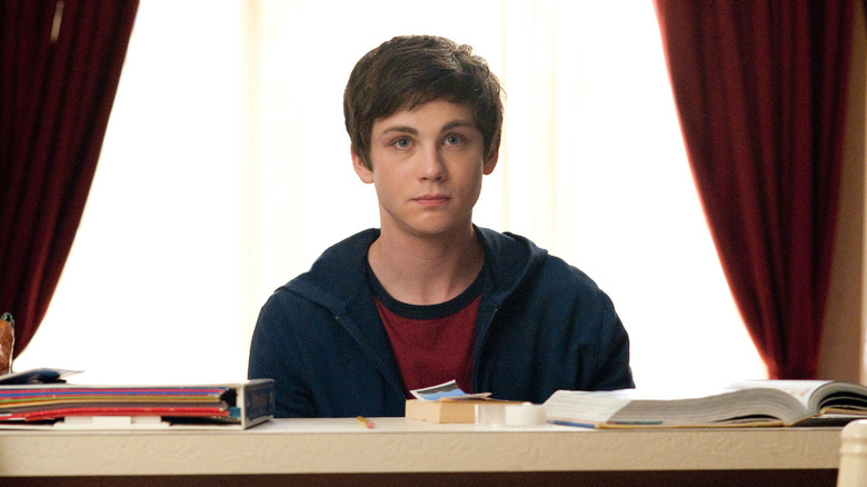 Charlie (Logan Lerman) sits at a table with his books in The Perks of Being a Wallflower