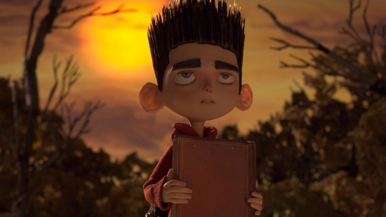 Norman Babcock (Kodi Smit-McPhee) holds a spellbook in the woods in ParaNorman