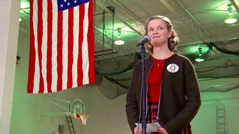 Reese Witherspoon as Tracey Flick making a speech in front of the American flag in Election