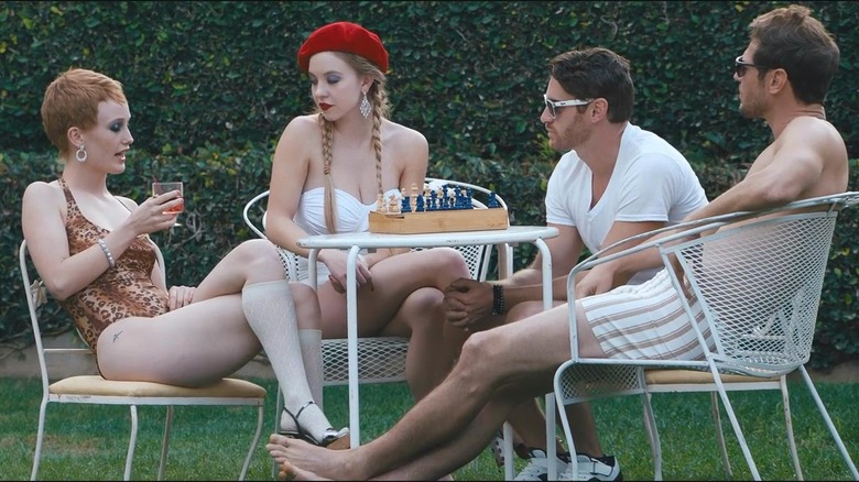 Sydney Sweeney as Shooting Star #2 sitting at a white table with a woman and two men in Under the Silver Lake