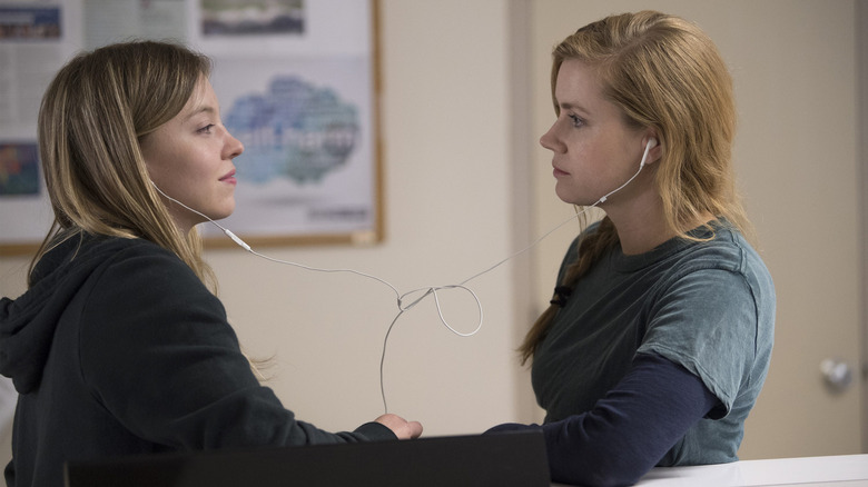 Sydney Sweeney as Alice and Amy Adams as Camille looking at each other and sharing headphones in Sharp Objects