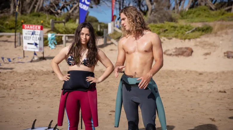 Summer Torres (Sky Katz) gets surfing advice from Ari Gibson (Kai Lewins) on the beach in Surviving Summer