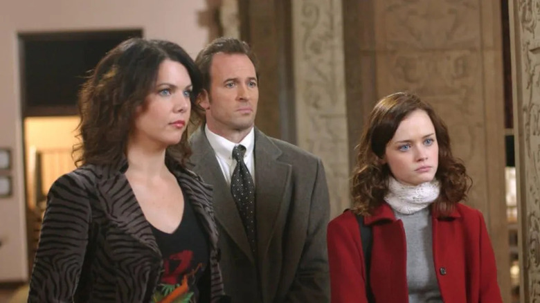 Lorelai (Lauren Graham) and Rory (Alexis Bledel) stand next to Luke (Scott Patterson) on Gilmore Girls