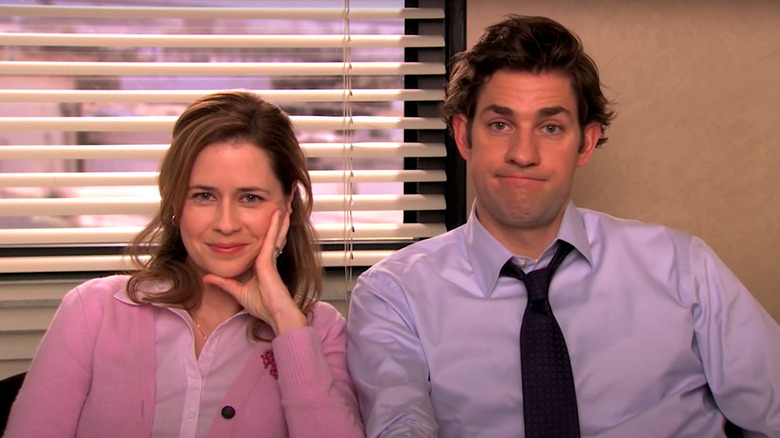 Pam (Jenna Fischer) smiles sitting next to Jim (John Krasinski) on The Office