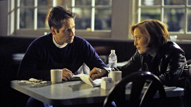 Fox Mulder (David Duchovny) sits next to Dana Scully (Gillian Anderson) on The X-Files