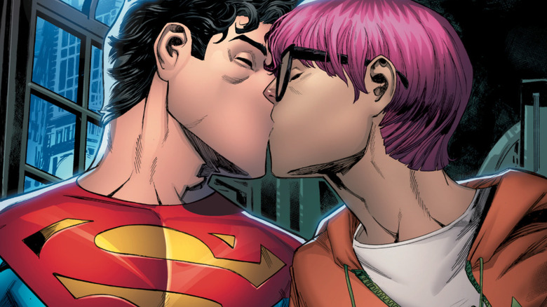 Jon Kent (wearing Superman costume) kissing man with pink hair and glasses in comic