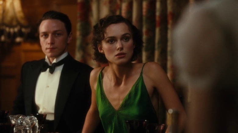 Keira Knightley as Cecilia Tallis and James McAvoy as Robbie Turner sitting at a table with disturbed expressions in Atonement