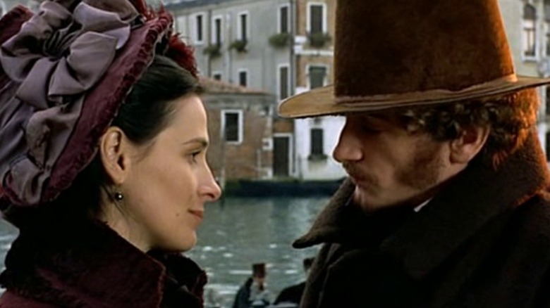 Juliette Binoche as George Sand and Benoît Magimel as Alfred de Musset locking eyes by a pier in The Children of the Century